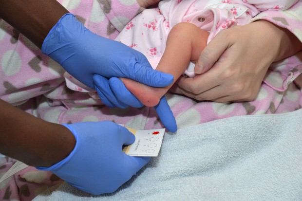 A health professional carrying out a newborn blood spot test on a baby.