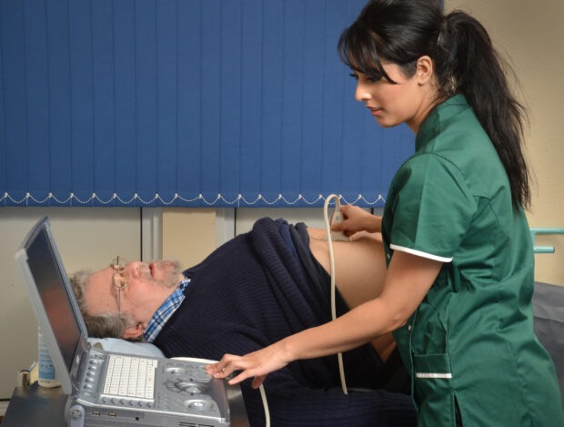 A woman screens a man to show the AAA screening test taking place