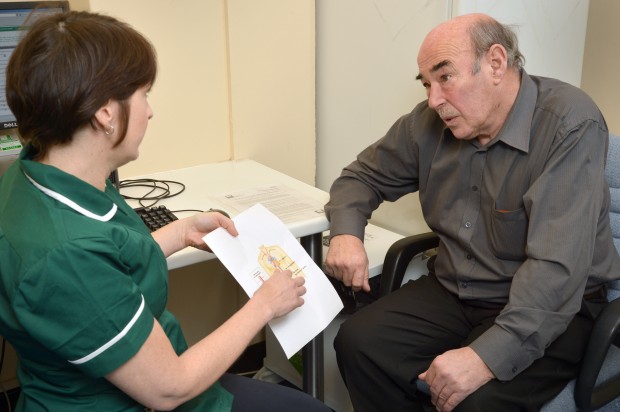 A health professional explaining AAA screening to a man.