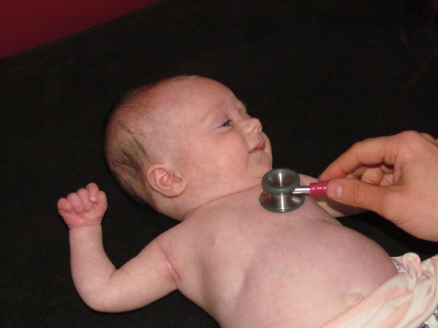 A newborn baby having its chest examined with a stethoscope.