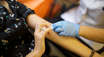 A nurse takes a blood sample from a woman's arm.