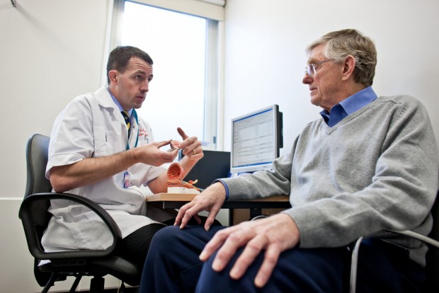 A GP talking to an older male patient.