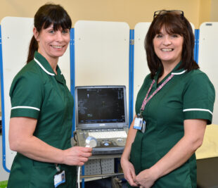 Two Abdominal Aortic Aneurysm Screeners smiling in front of their equipment