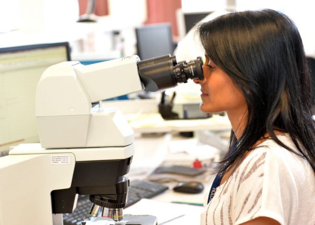 A woman looking down a microscope