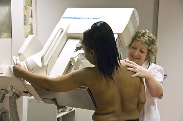 A woman having a breast screening mammography taken by another woman.