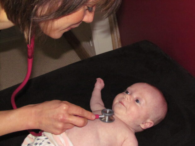 A baby having its heart checked with a stethoscope