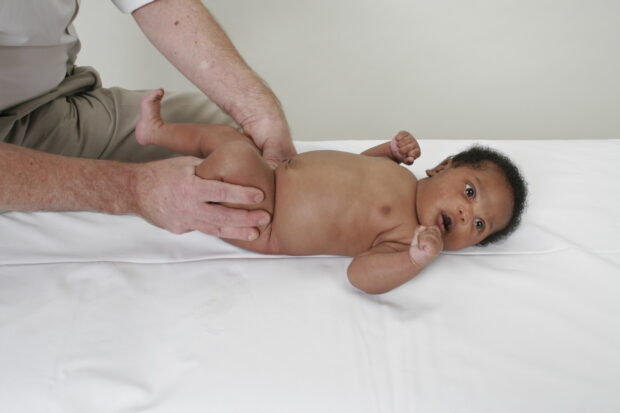 Someone checking a baby's hips as part of the newborn and infant physical examination.