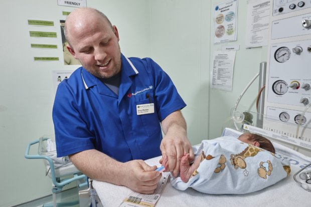 A midwife taking a newborn blood spot sample from a baby's heel.