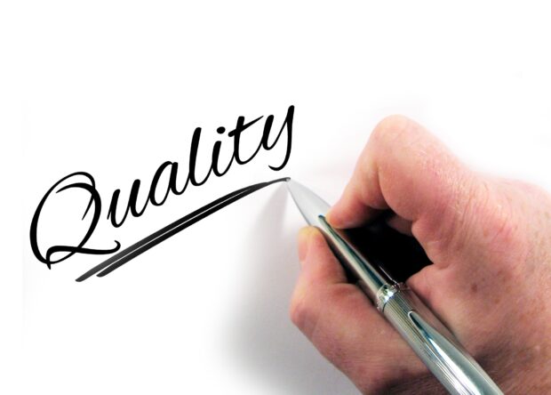 A person writes out the word 'quality' on the page to illustrate the face that the consolidated standards are all about maintaining quality.