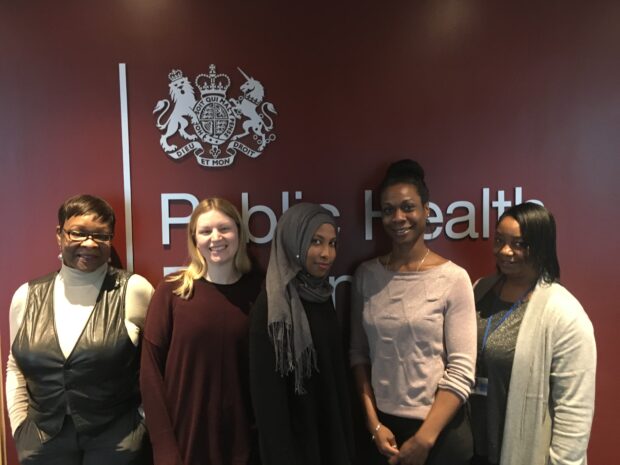 The 5 members of the helpdesk team standing in front of the PHE logo.
