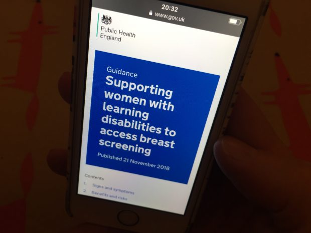 Photo shows a person holding a mobile phone displaying the words Supporting women with learning disabilities to access breast screening.