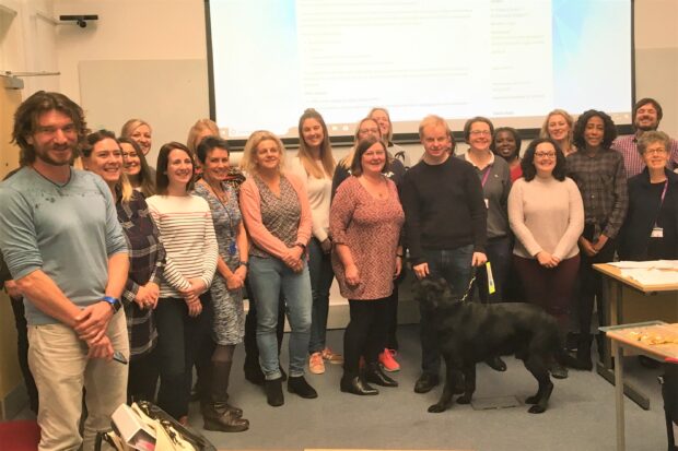 Photo shows a group of about 22 Warwick health screening attendees and course tutors in a classroom.