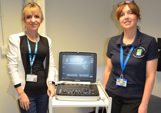 2 women standing by an ultrasound machine used for AAA screening tests