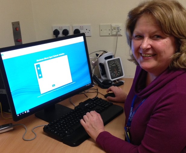 A female screening coordinator sitting at a desk in an office with a screen in front of her which is set up with the first page of the Newborn Blood Spot Failsafe Solution