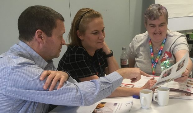 Publications and information manager Mike Harris showing the draft bowel cancer screening easy guide to expert by experience Leanne and support worker Michelle