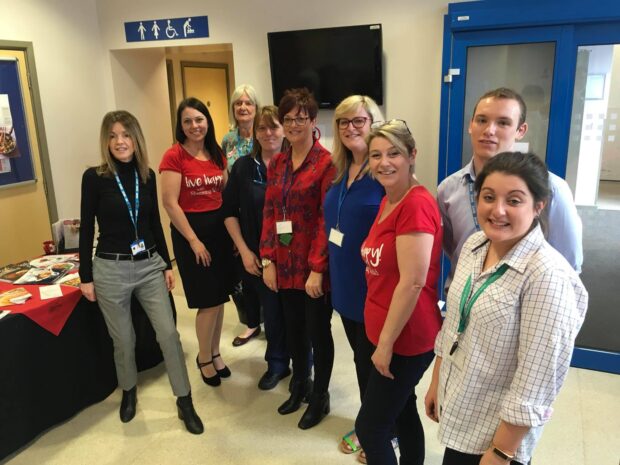 Diabetic eye screening staff with other health professionals standing in a room smiling at the camera