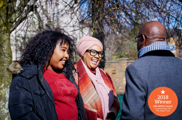 Two women talking and laughing with John James, chief executive of Sickle Cell Society