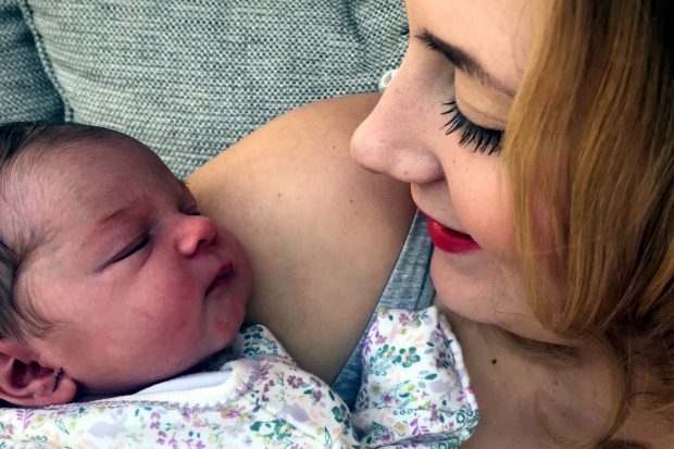 A close up of a young women holding a newborn baby