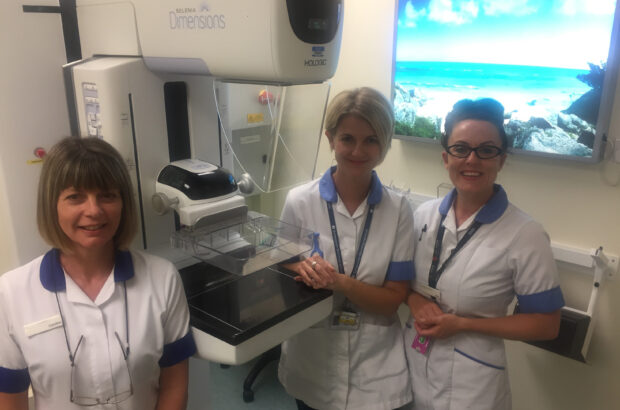 Gina Newman, right, with clinical colleagues Caroline Hanlon (senior radiographer) and Dawn Rowley (advanced assistant practitioner) in front of a breast screening machine in a clinic room