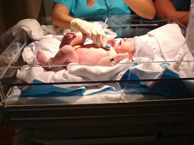 Photo of a newborn baby being examined in hospital by a nurse.