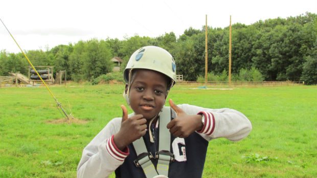 Boy has helmet on because he has been doing outdoor pursuits and has two thumbs up