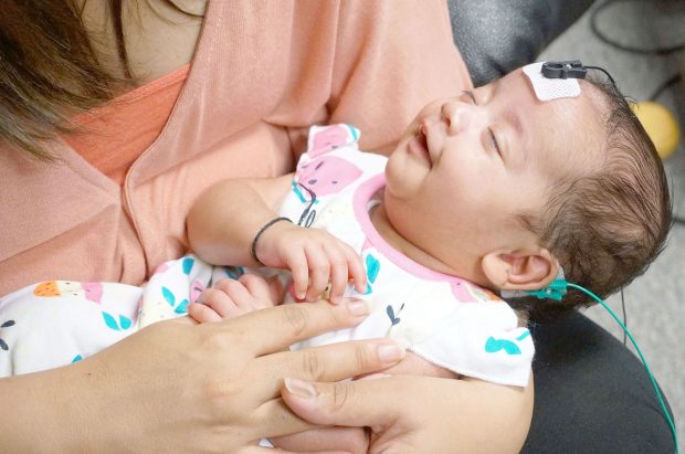 A mother holds her baby at an audiology appointment