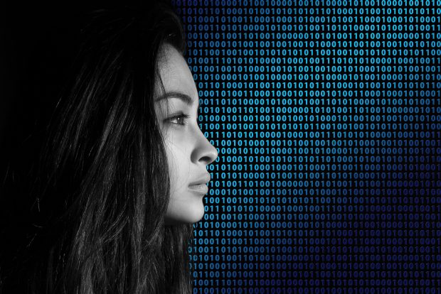 A woman's head in front of binary code showing zeroes and ones