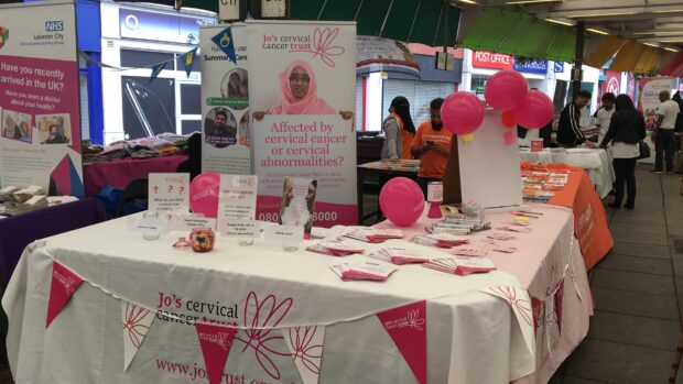 A presentation stand has materials about cervical screening, including bunting and balloons.