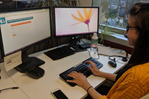 A colleague sits at her desk, logging into the NBSFS system