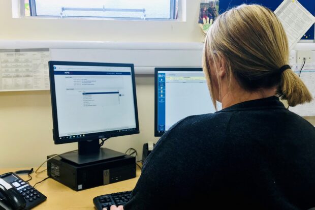 A woman sitting in front of a computer screen with her hands on the keyboard