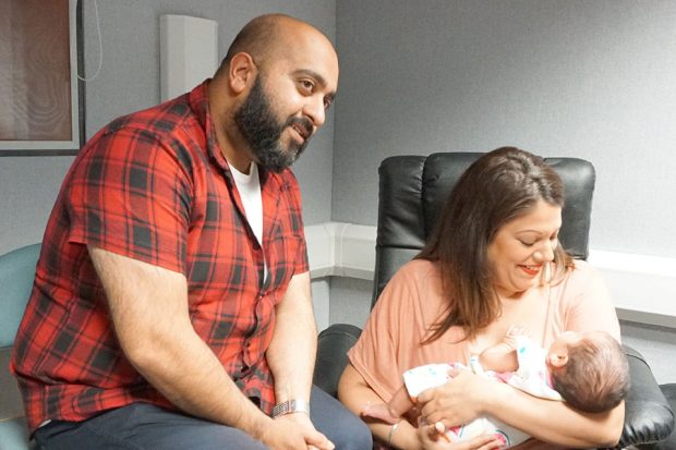 Father and mother with sleeping baby at an audiology appointmentms receiving hearing test at an audiology appointment