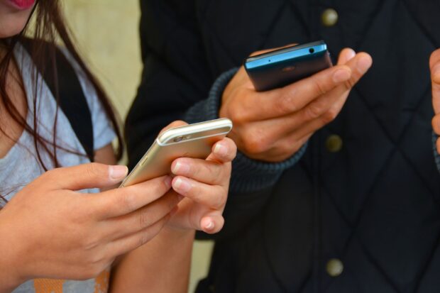 Two people holding mobile phones to send text messages