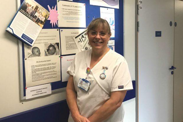 A screener, Hayley Buckley, standing in front of a notice board for newborn hearing screening