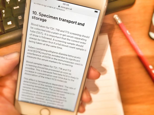 Hand holding a mobile phone with the page for specimen transport and storage.