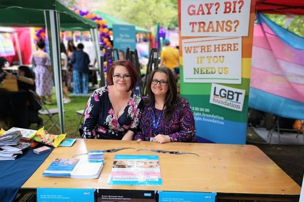 Two women (Alex Matheson and Sara Gill) sitting at a desk at a lesbian, gay, bisexual and transsexual event