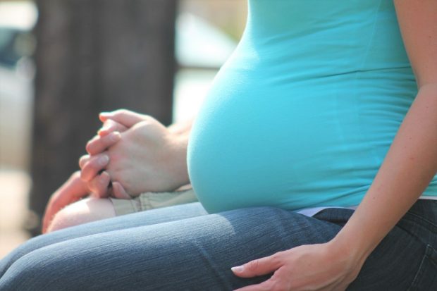 A pregnant woman sitting down holding a person's hand