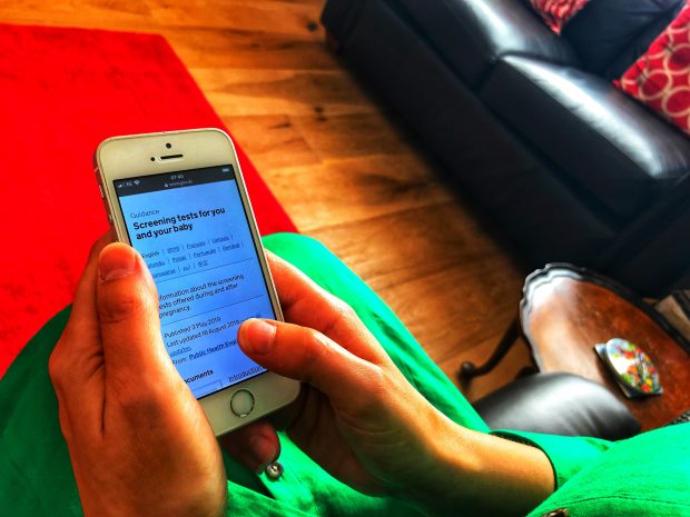 Women looks at her mobile phone to access screening information.