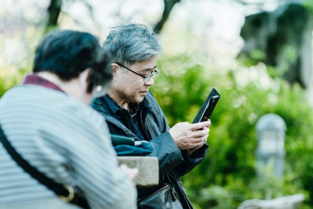 Two older people checking their mobile phones