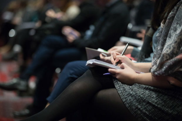 A row of people with pens and notebooks.