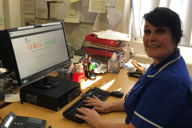 A health professional at a computer with the ISOSS online portal displayed on screen.